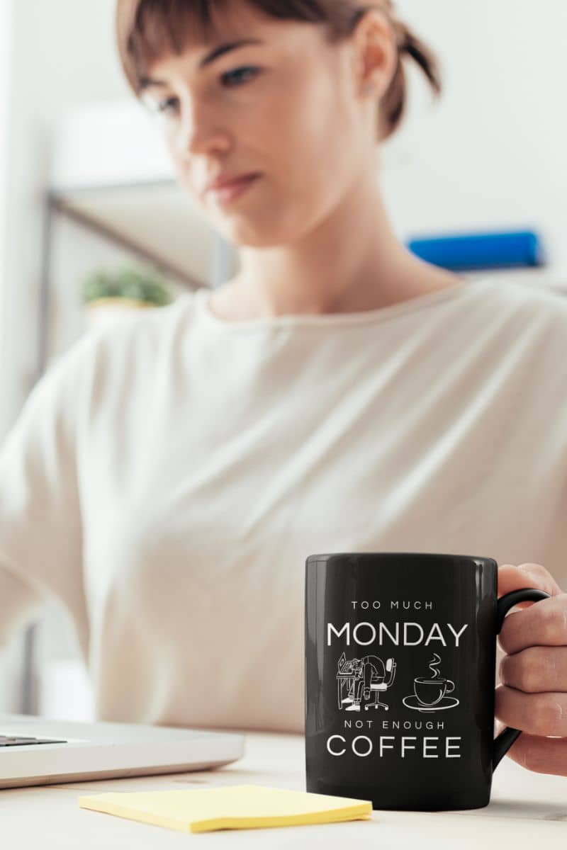 Too much monday mug with a girl holding a cup of coffee while working on a laptop