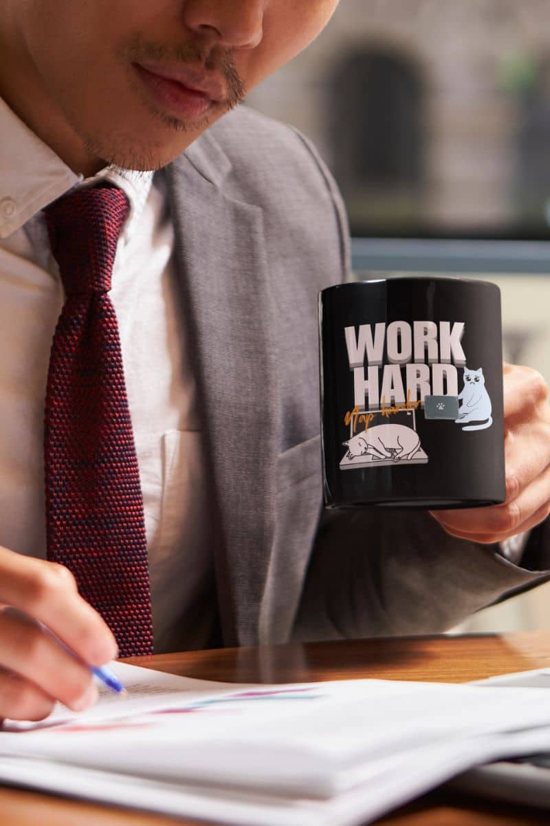 Work hard, nap harder mug with an office worker working while still holding a cup of coffee in his hand