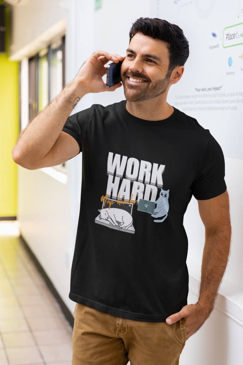 Work hard, nap harder t-shirt with a guy standing talking on the phone outside the office hallway