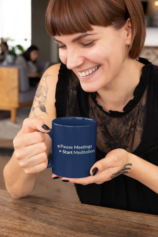 Zen coffee mug with a woman holding a blue mug with text, sitting at a table indoors.