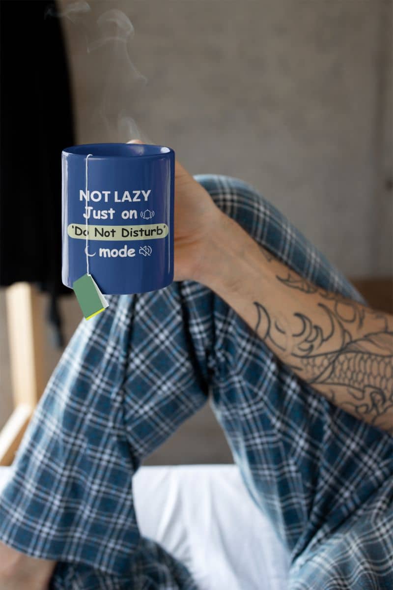 anti social mug with a person holding a blue device labeled 'Not Lazy' with text on it, sitting in a chair.