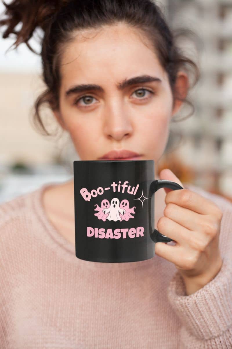 boo crew mug with a person holding a black mug with 'Boo-tiful Disaster' text and ghost design.