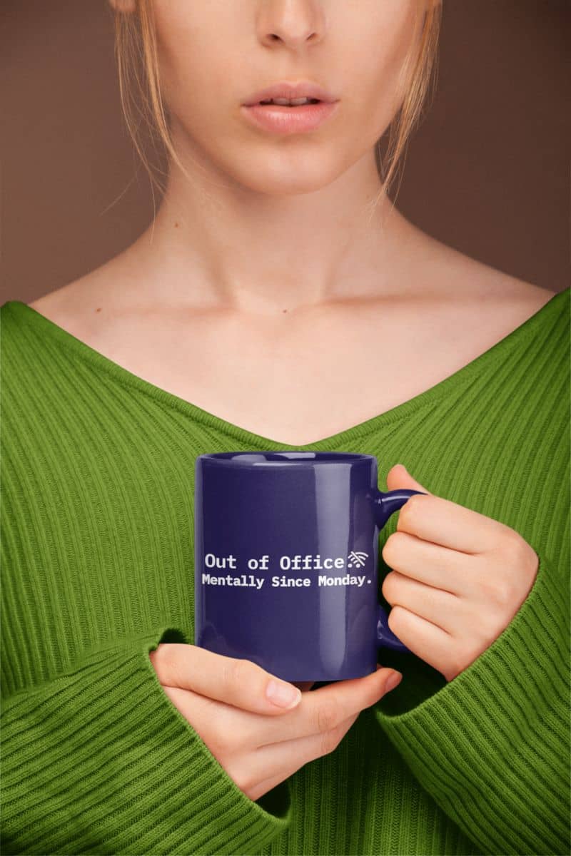 caffeine and coping mug with a person holding a blue mug with text, wearing a green sweater against a brown background