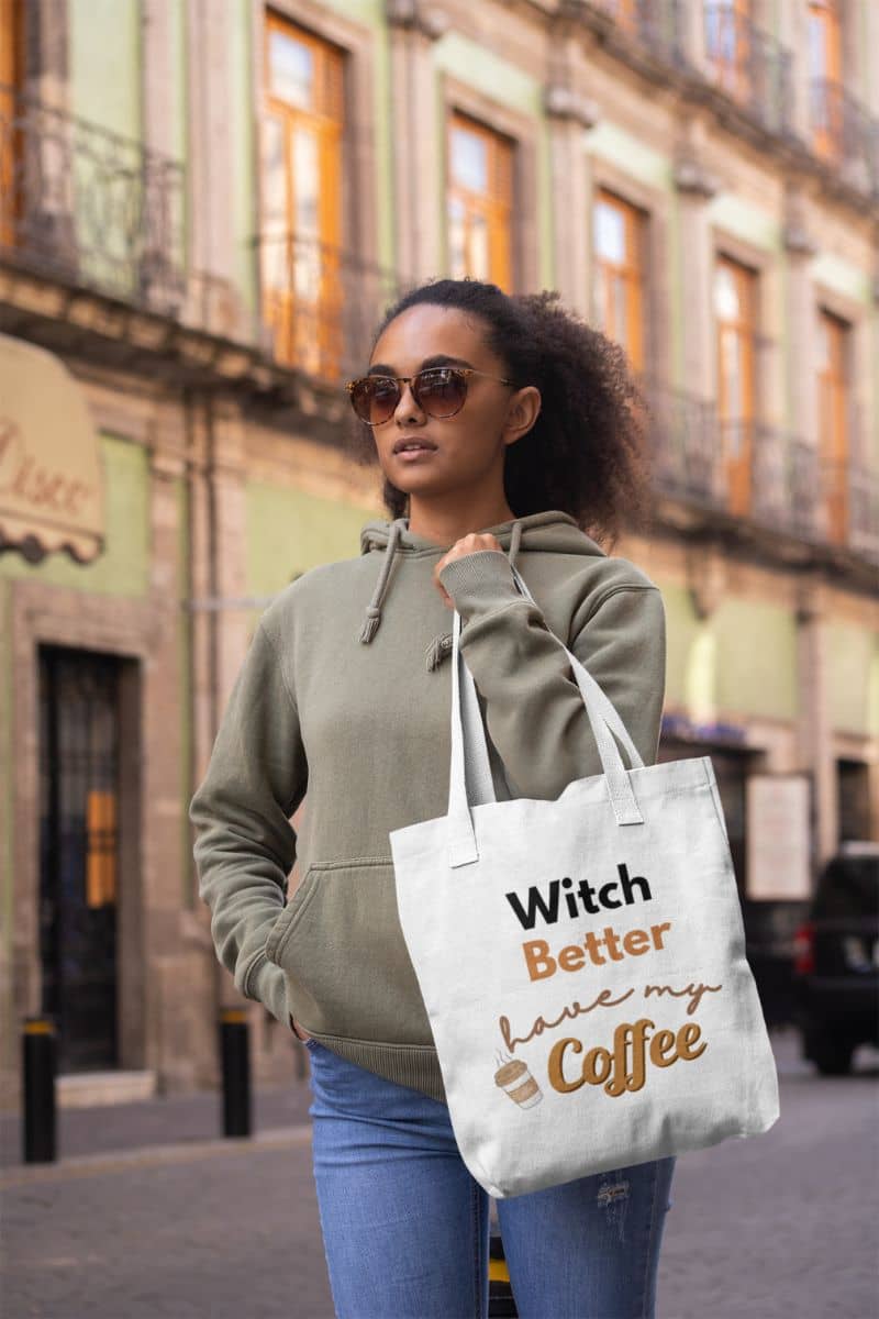 caffeine lover bag with a woman holding a tote bag with text 'Witch Better Have My Coffee' on a city street