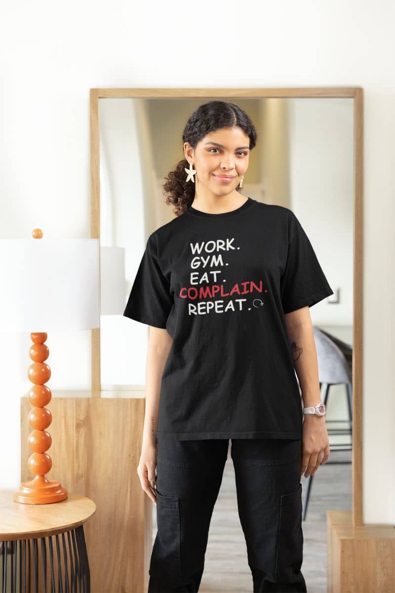 casual everyday outfit shirt with a person wearing a black t-shirt with text in a room with a mirror and decor.