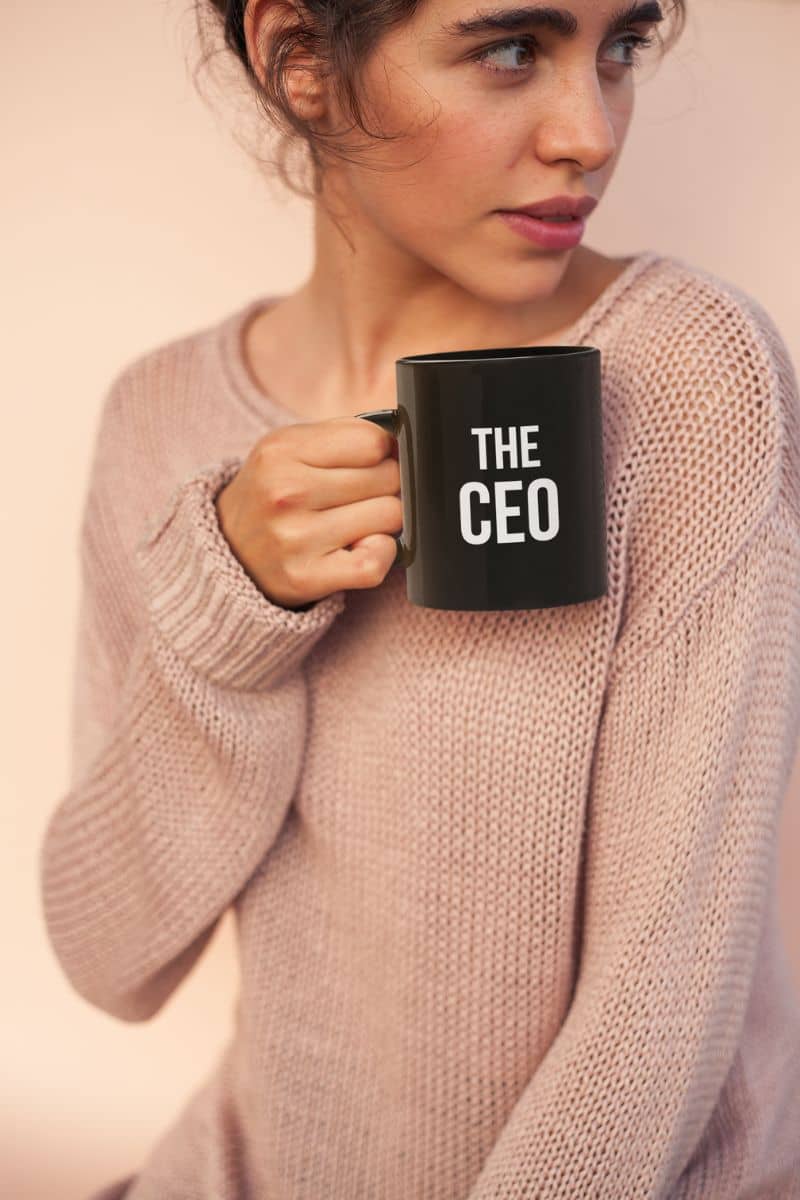 ceramic coffee mug gift with a woman holding a black mug with 'THE CEO' text against a plain background