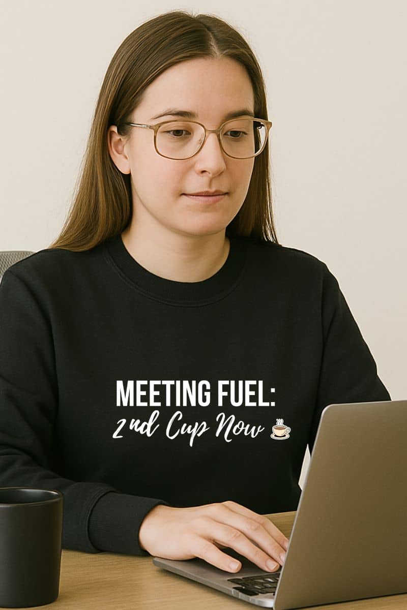 coffee quote sweatshirt with a person wearing a black sweatshirt with text sitting at a laptop.