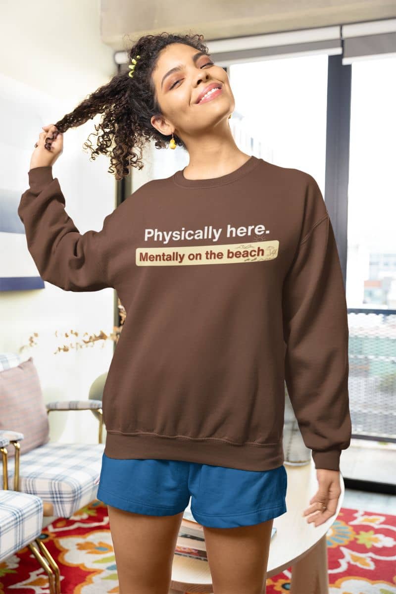 cozy beach vibes pullover with a woman wearing a brown sweatshirt with text, standing in a living room.
