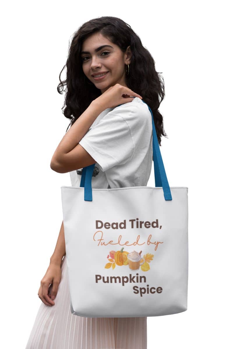 cozy canvas bag with a woman holding a tote bag with 'Dead Tired, Fueled by Pumpkin Spice' text and graphics.