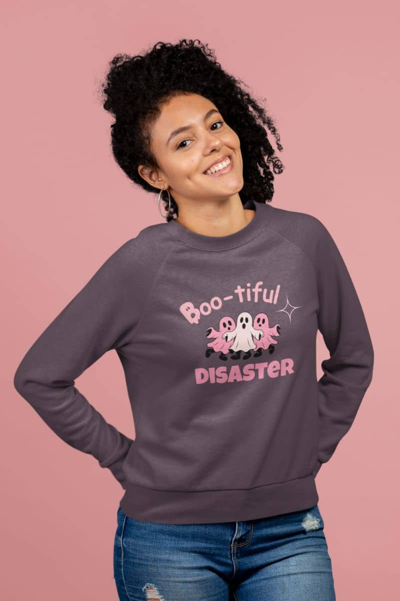 fall spooky pullover with a person wearing a sweatshirt with 'Boo-tiful Disaster' design on a pink background
