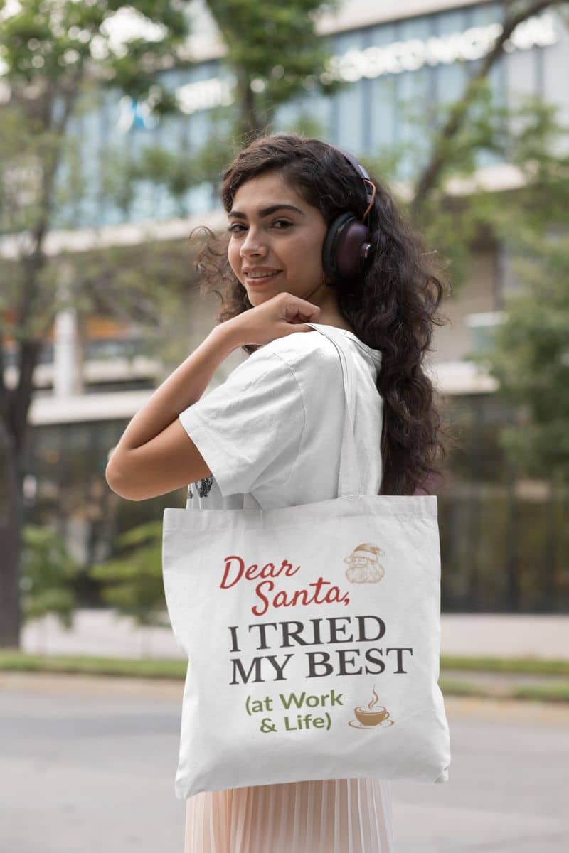 festive reusable tote with a woman wearing headphones and holding a tote bag with a humorous message outdoors.