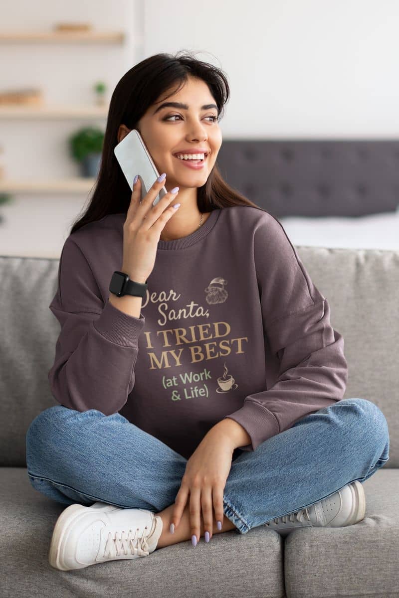 funny christmas sweater with a woman sitting on a couch wearing a sweatshirt with text 'Dear Santa, I tried my best (at work & life)', talking on a phone.