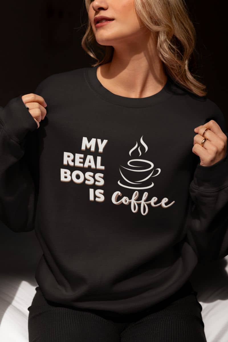 funny coffee sweatshirt with a person wearing a black sweatshirt with 'My Real Boss is Coffee' text and graphic.