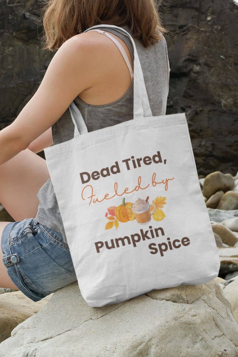funny fall tote with a person holding a tote bag with pumpkin spice text and graphics on a rocky surface