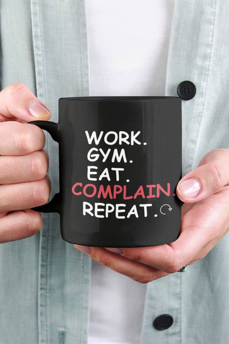 funny office mug with a person wearing a light blue jacket holding a mug with text 'Work. Gym. Eat. Complain. Repeat'