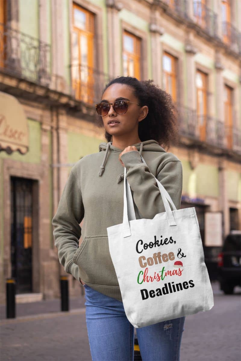 funny work tote with a woman holding a tote bag with text 'Cookies, Coffee & Christmas Deadlines' in an urban setting