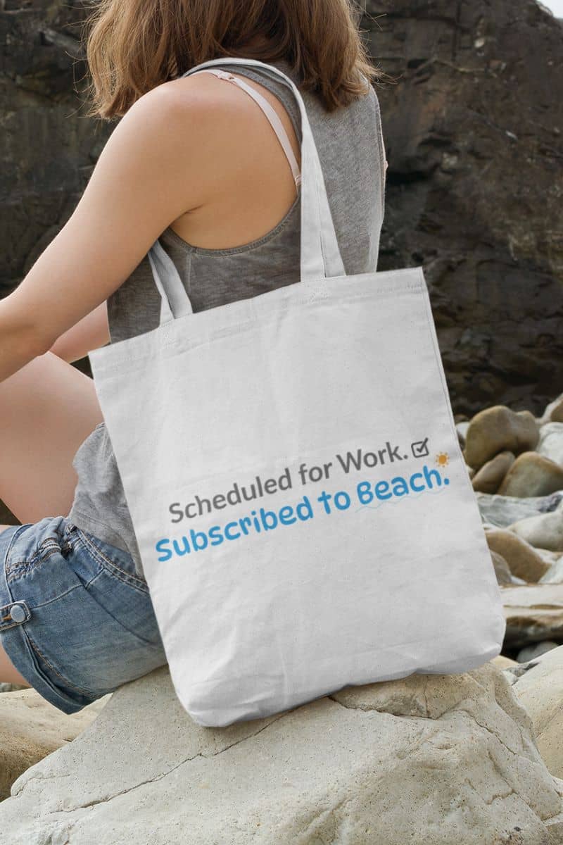 gym tote bag with a person sitting on rocks with a tote bag that says 'Scheduled for Work, Subscribed to Beach'.