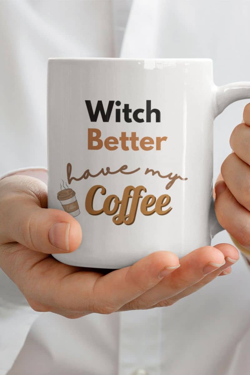 halloween coffee cup with a mug with 'Witch Better Have My Coffee' text held by hands against a white background