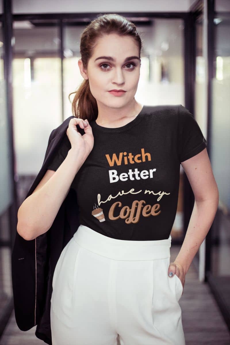 halloween coffee shirt with a woman wearing a black t-shirt with text 'Witch Better Have My Coffee', standing in an indoor setting.