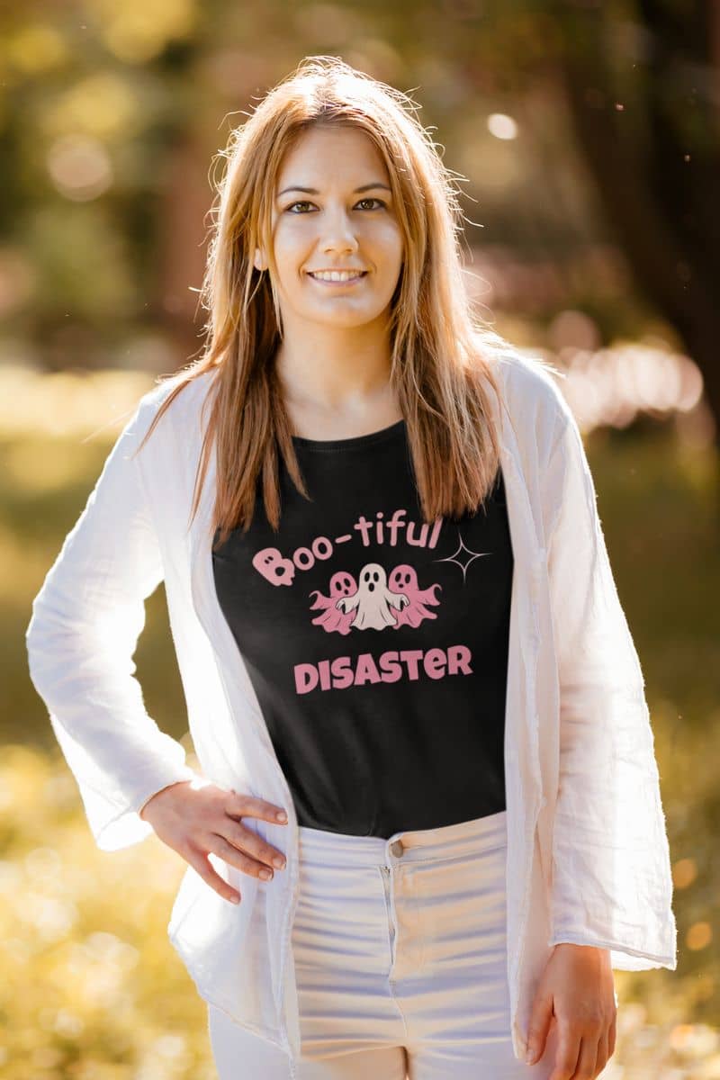 halloween graphic top with woman wearing a black t-shirt with 'Boo-tiful Disaster' text and graphics outdoors.