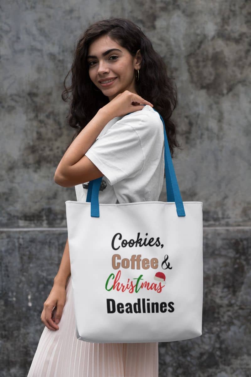 holiday office tote with a woman holding a tote bag with text 'Cookies, Coffee & Christmas Deadlines' against a textured wall.