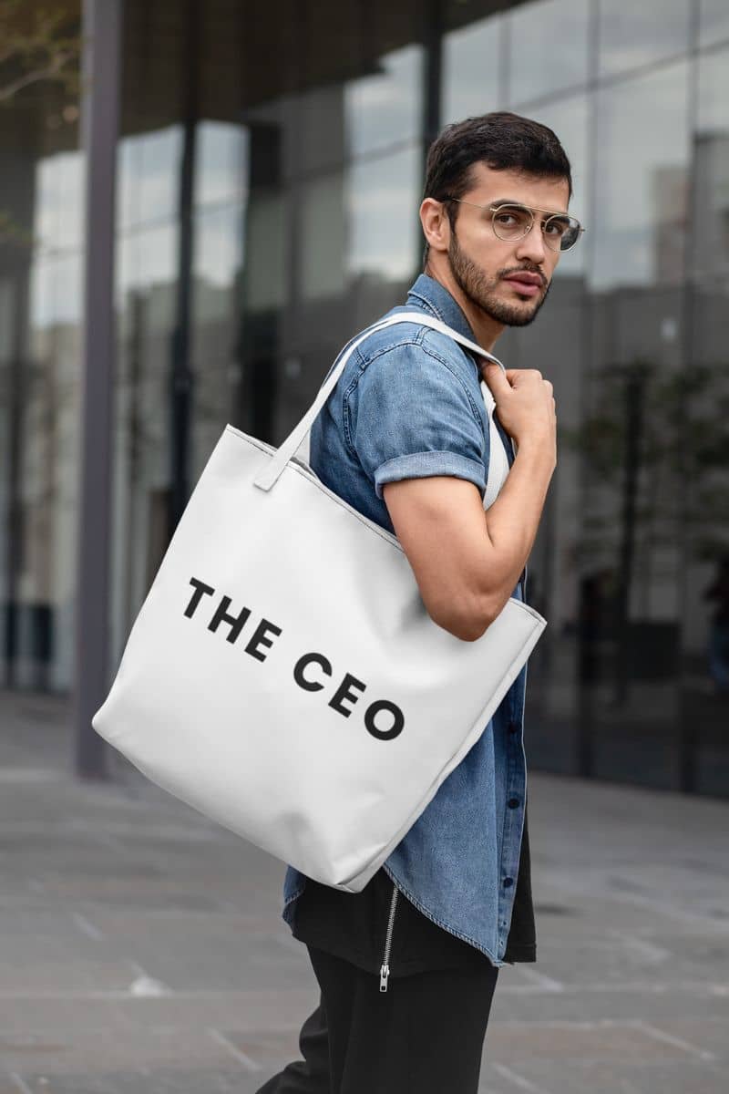 neutral color canvas bag with a man holding a white tote bag with 'THE CEO' text outdoors.
