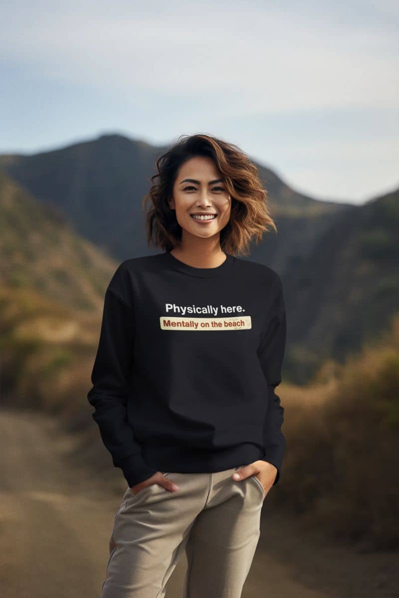 ocean breeze sweatshirt with a person wearing a black sweatshirt with text, standing in front of mountains.