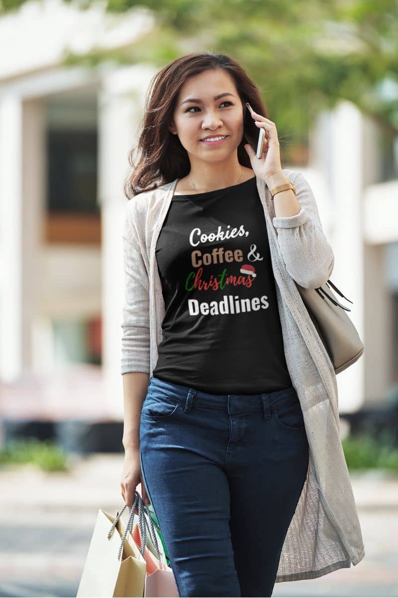 office christmas outfit with a woman walking outdoors wearing a black t-shirt with text, holding a phone to her ear.