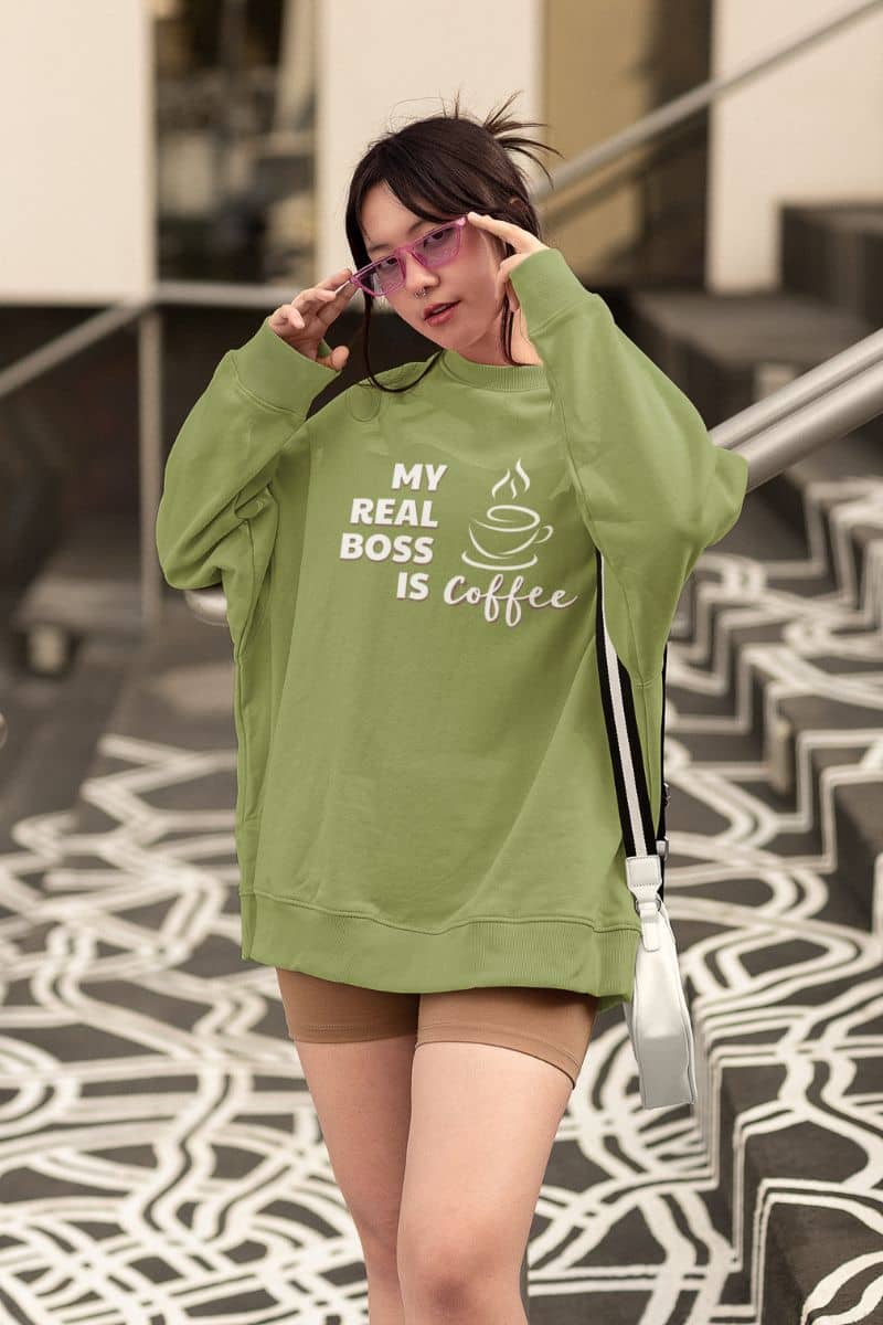 oversized coffee sweatshirt with a person wearing a green sweatshirt with text, standing on a patterned floor.