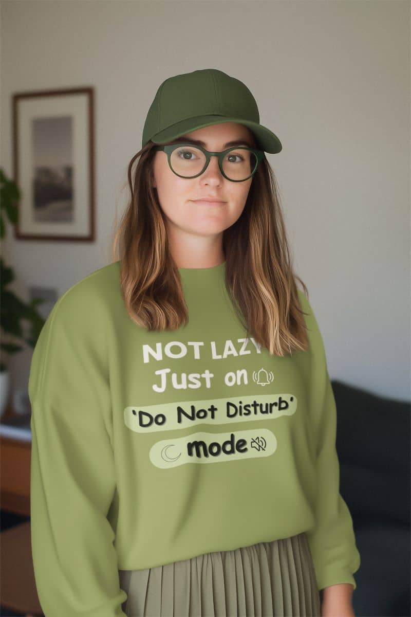 quiet mode sweatshirt with a person wearing a green sweatshirt with text 'NOT LAZY, Just on 'Do Not Disturb' mode' and a cap indoors