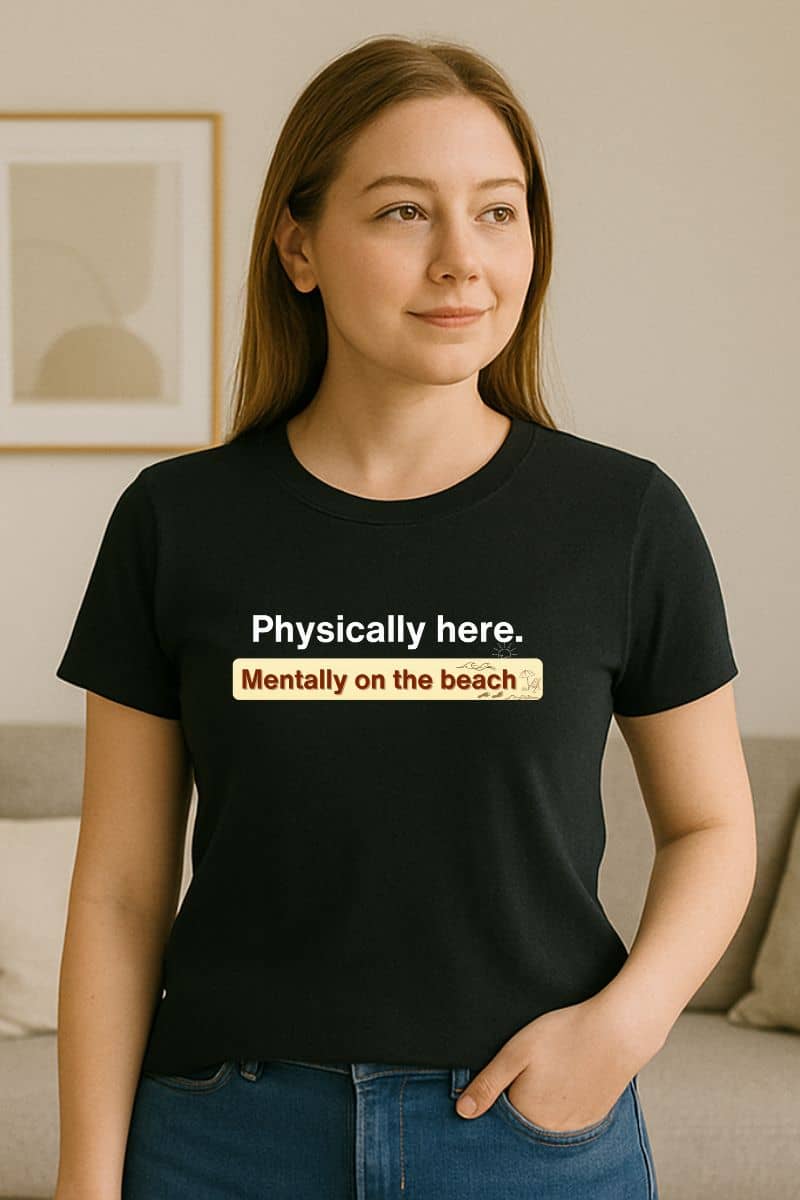 sarcastic beach quote tee with a person wearing a black t-shirt with text 'Physically here. Mentally on the beach.'