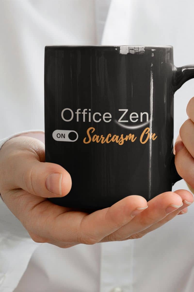 sarcastic spiritual quote mug - Black mug with 'Office Zen On Sarcasm On' text held by a person wearing a white shirt.
