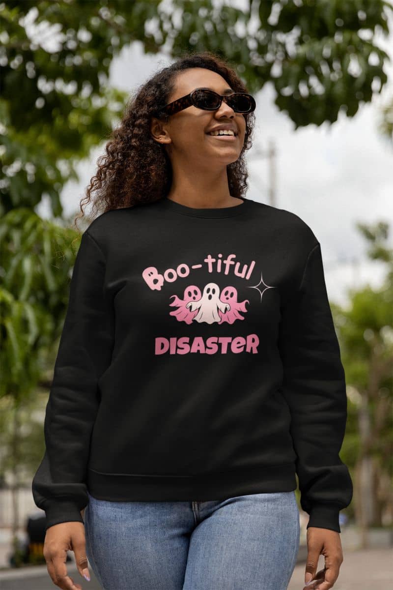 scary but cute sweatshirt with a person wearing a black sweatshirt with 'Boo-tiful Disaster' text and ghost graphics outdoors.