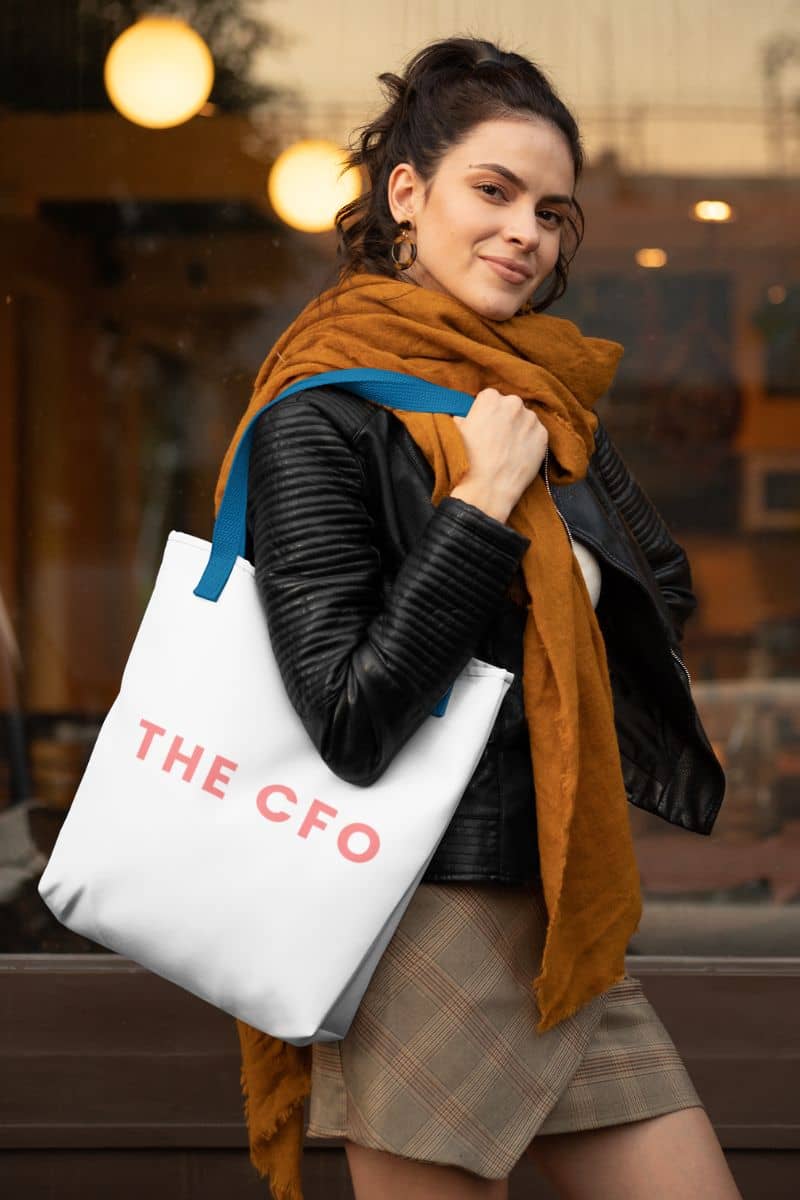 statement canvas tote with a woman holding a tote bag with 'THE CFO' printed on it, standing indoors.
