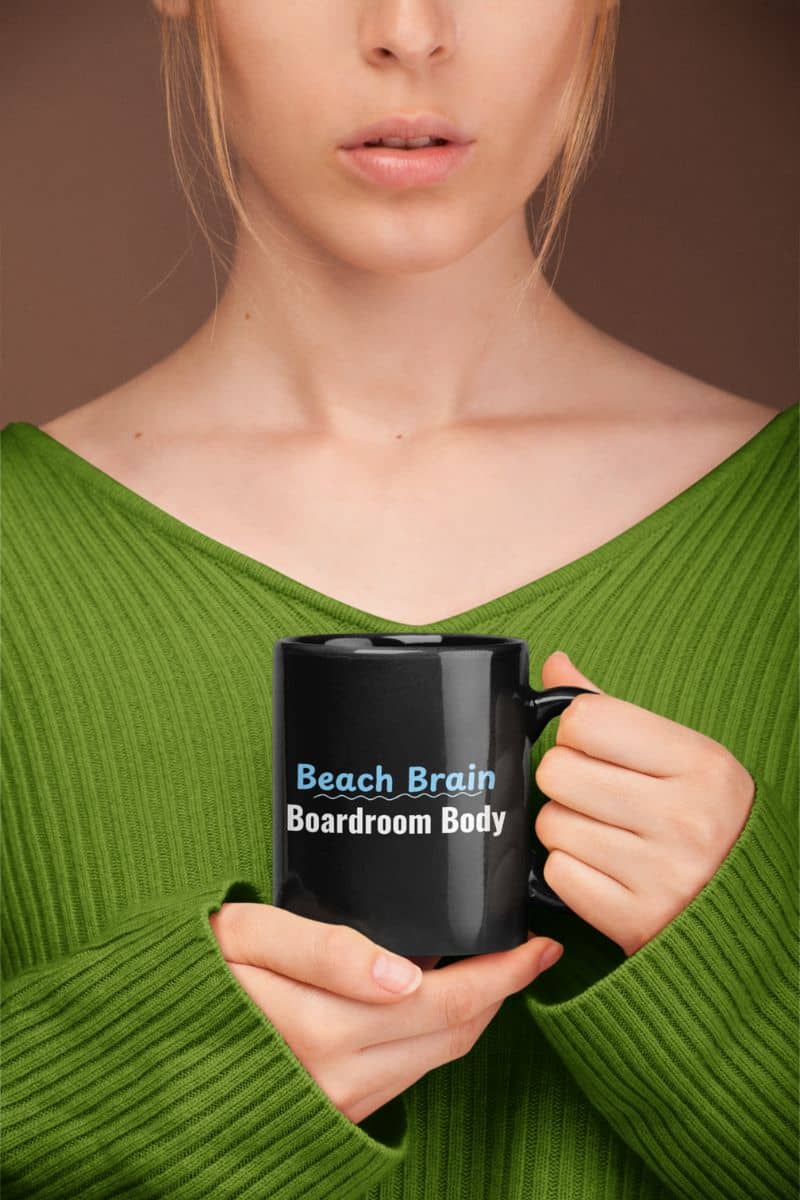 summer vacation coffee cup with a person holding a black mug with 'Beach Brain Boardroom Body' text, wearing a green sweater.