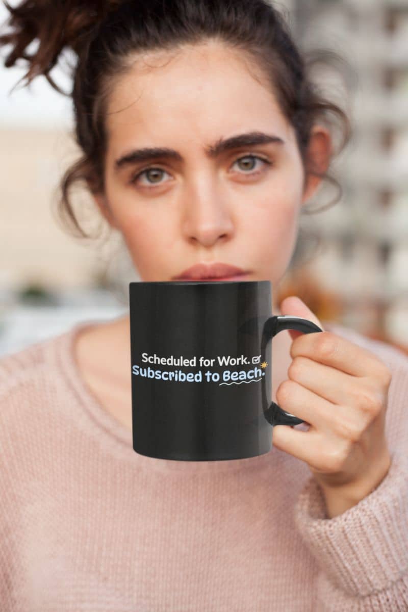 to go coffee mugs with a person holding a black mug, showing the text 'Scheduled for Work. Subscribed to Beach', wearing a light pink sweater.