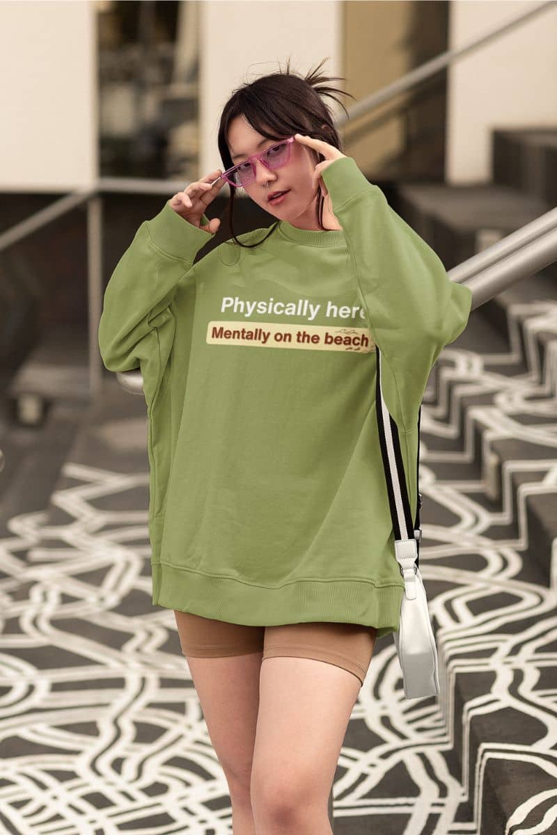 tropical escape sweatshirt with a person wearing a green sweatshirt with text, standing on a patterned floor.