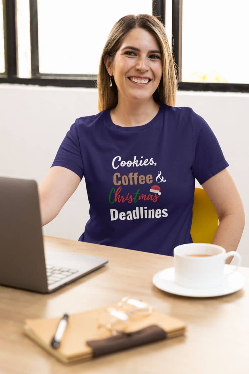 work humor shirt with a woman wearing a purple t-shirt with text sitting at a desk with a laptop and coffee.