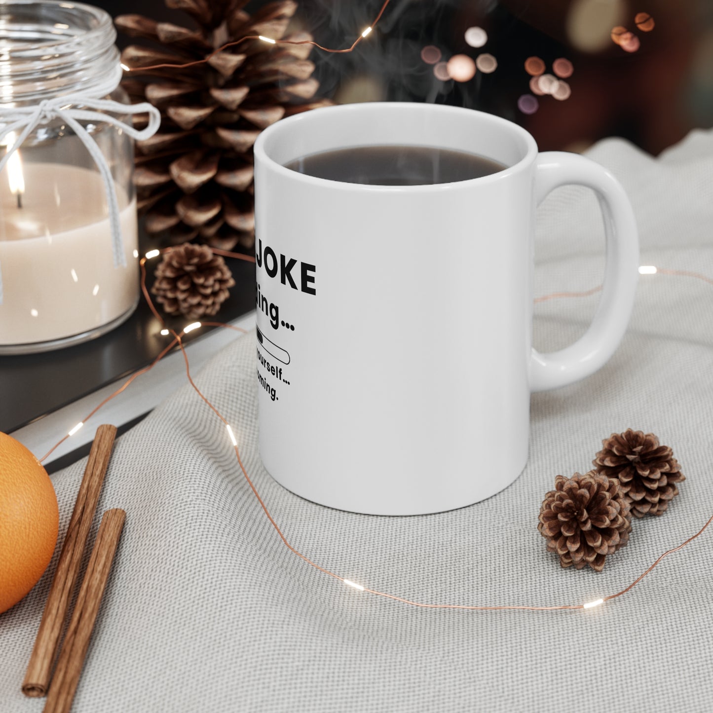 White mug with a design on a table with candles, oranges, and pine cones.