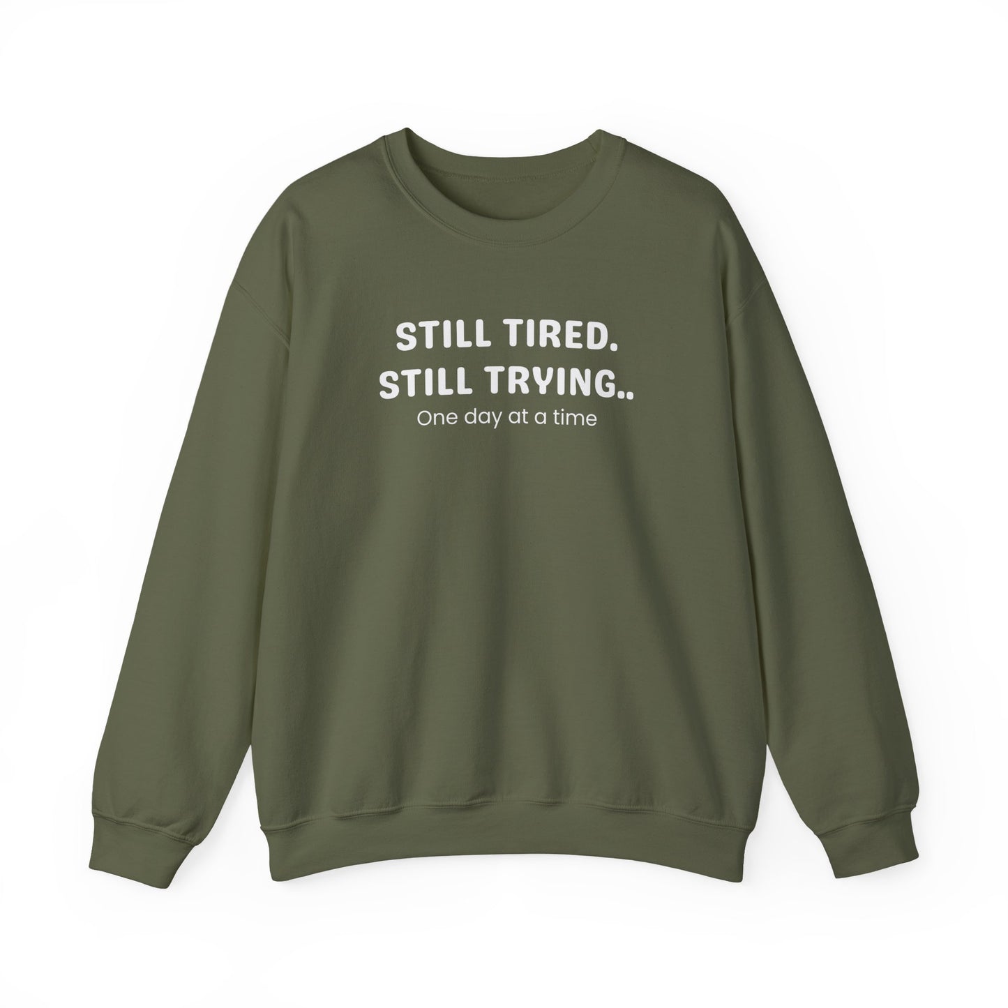 Green sweatshirt with text 'STILL TIRED. STILL TRYING.. One day at a time' on a white background