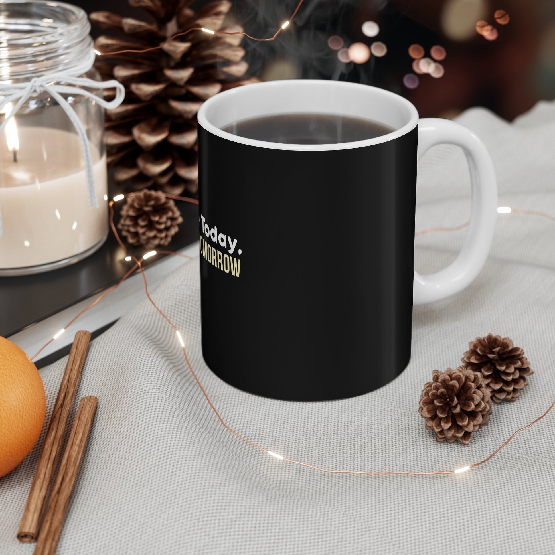 Black mug with text "Coffee Today, Survive Tomorrow" on a table with decorative items
