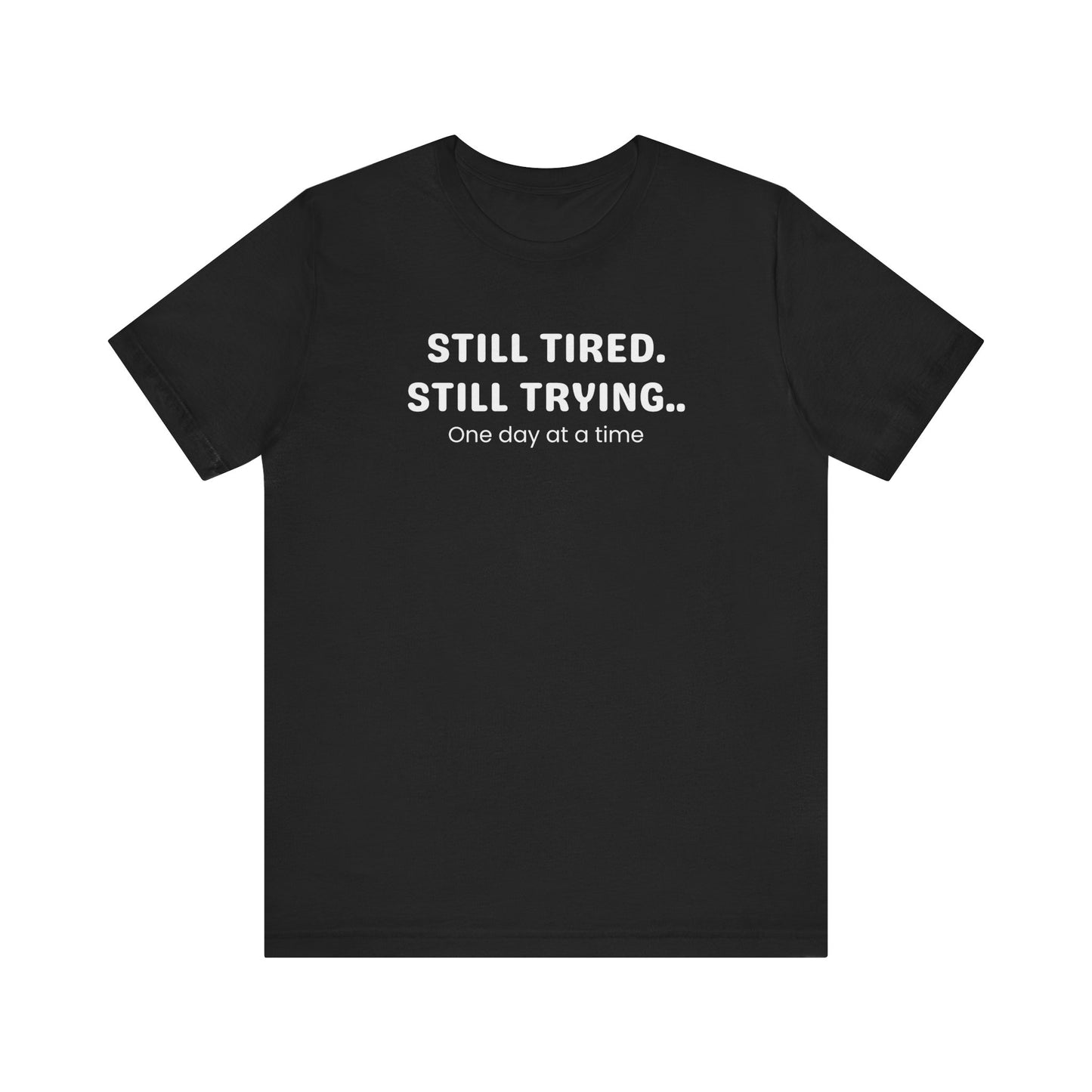 Black t-shirt with white text 'Still Tired. Still Trying. One day at a time' on a white background