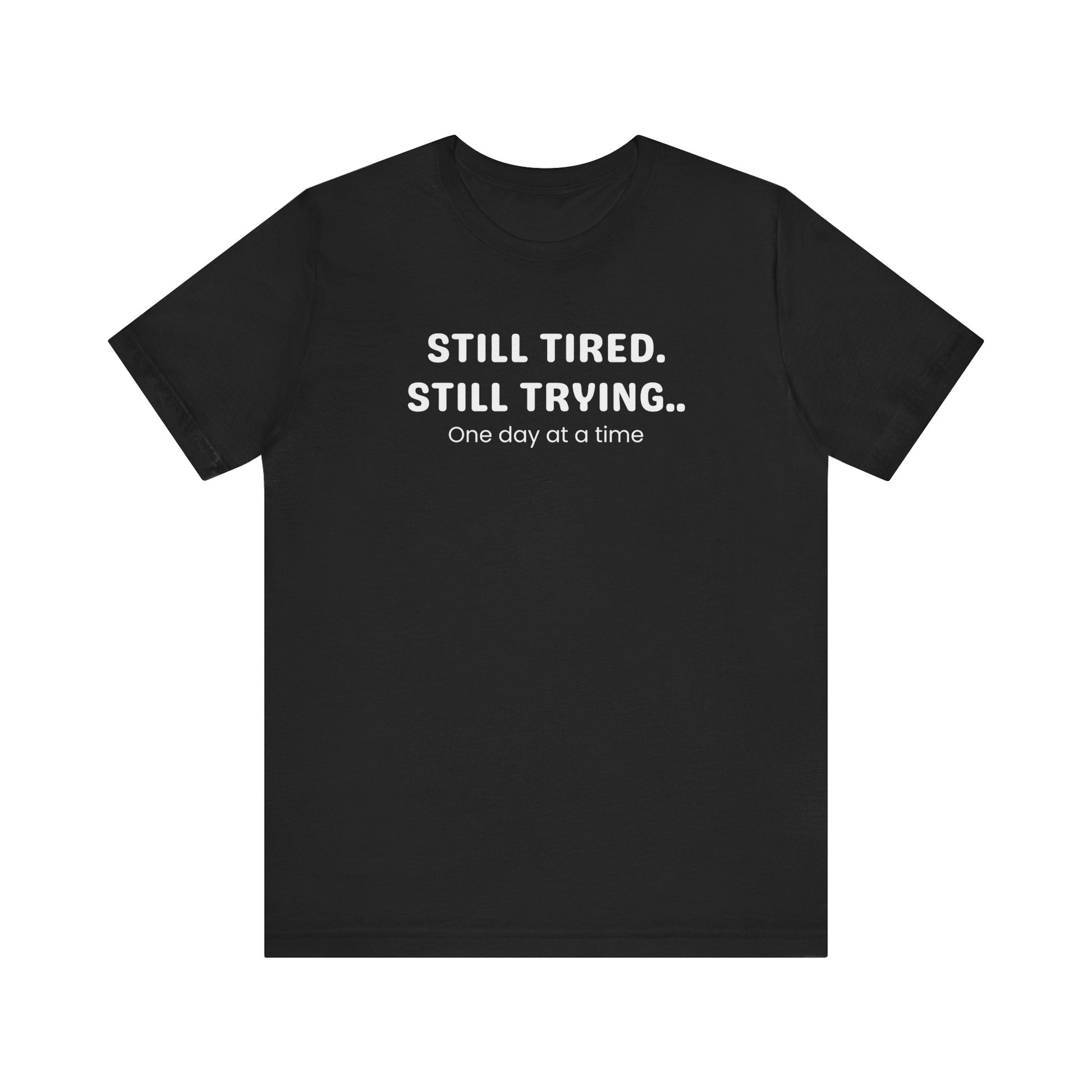 Black t-shirt with white text 'Still Tired. Still Trying. One day at a time' on a white background