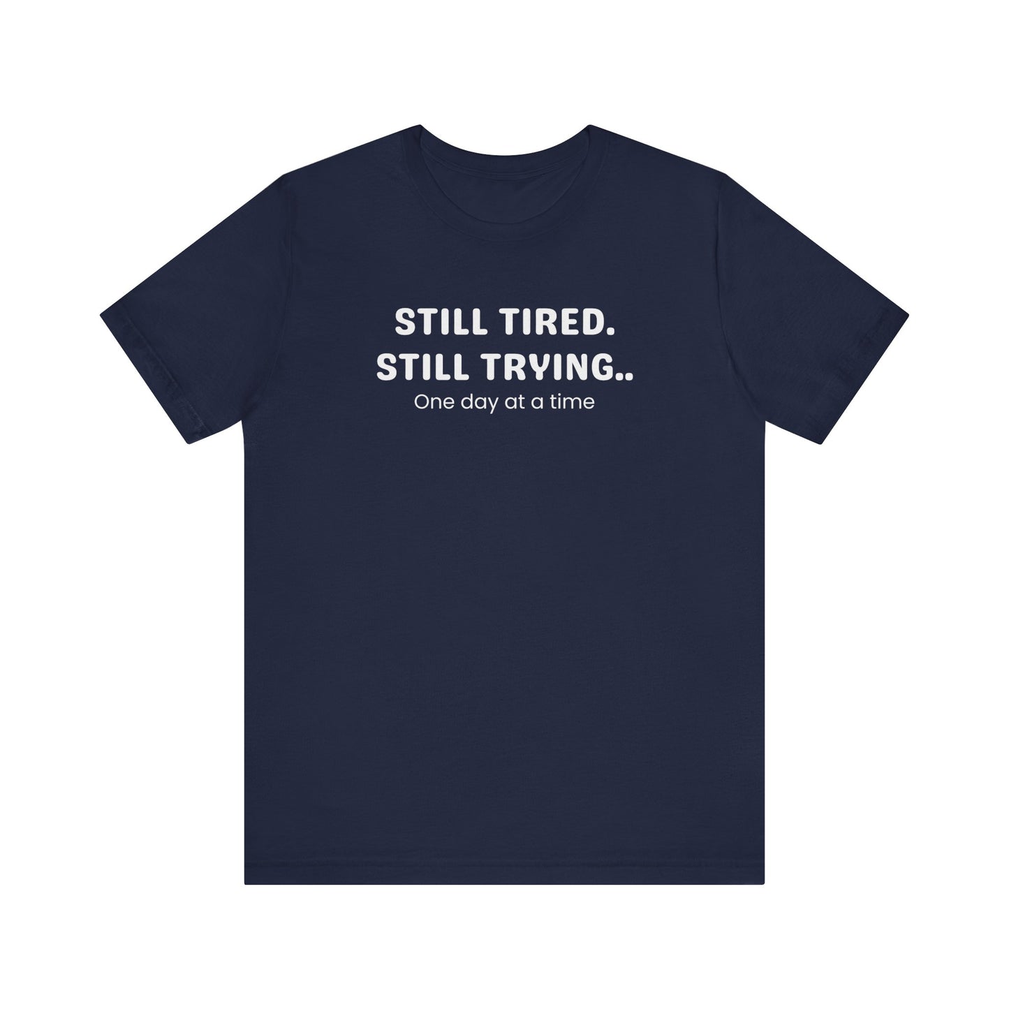 Navy t-shirt with white text 'Still Tired. Still Trying. One day at a time' on a white background