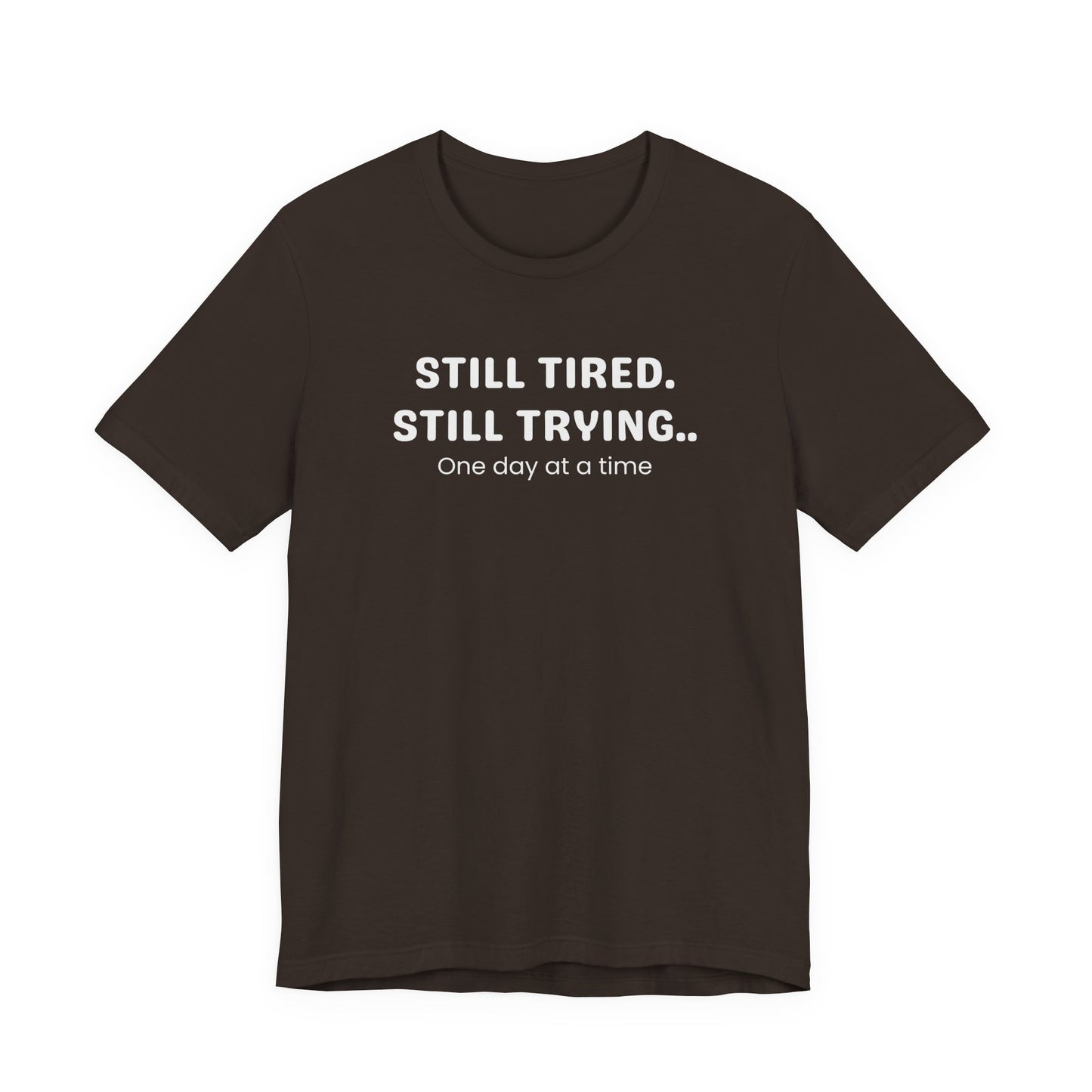 Brown t-shirt with white text 'Still Tired. Still Trying. One day at a time' on a white background