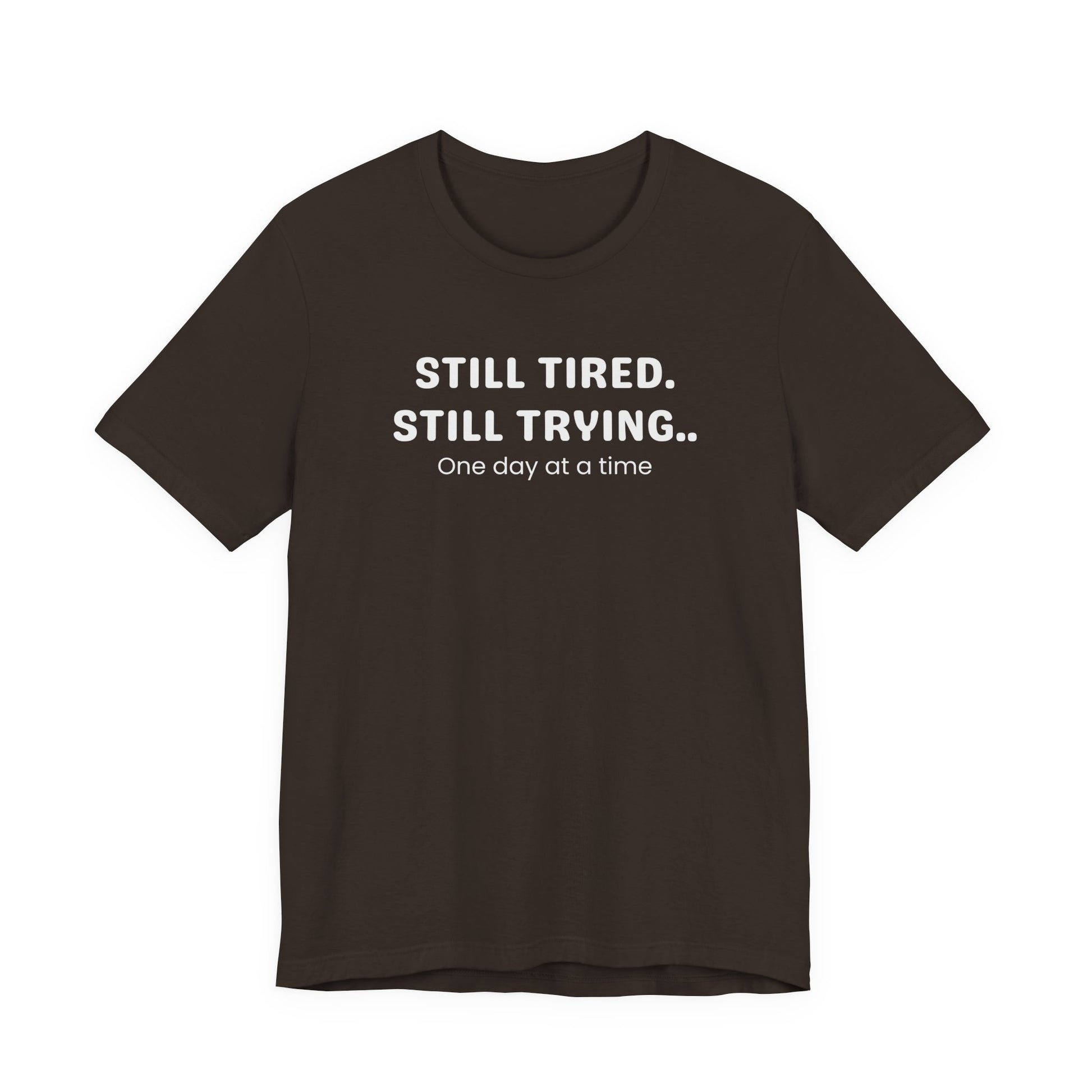 Brown t-shirt with white text 'Still Tired. Still Trying. One day at a time' on a white background