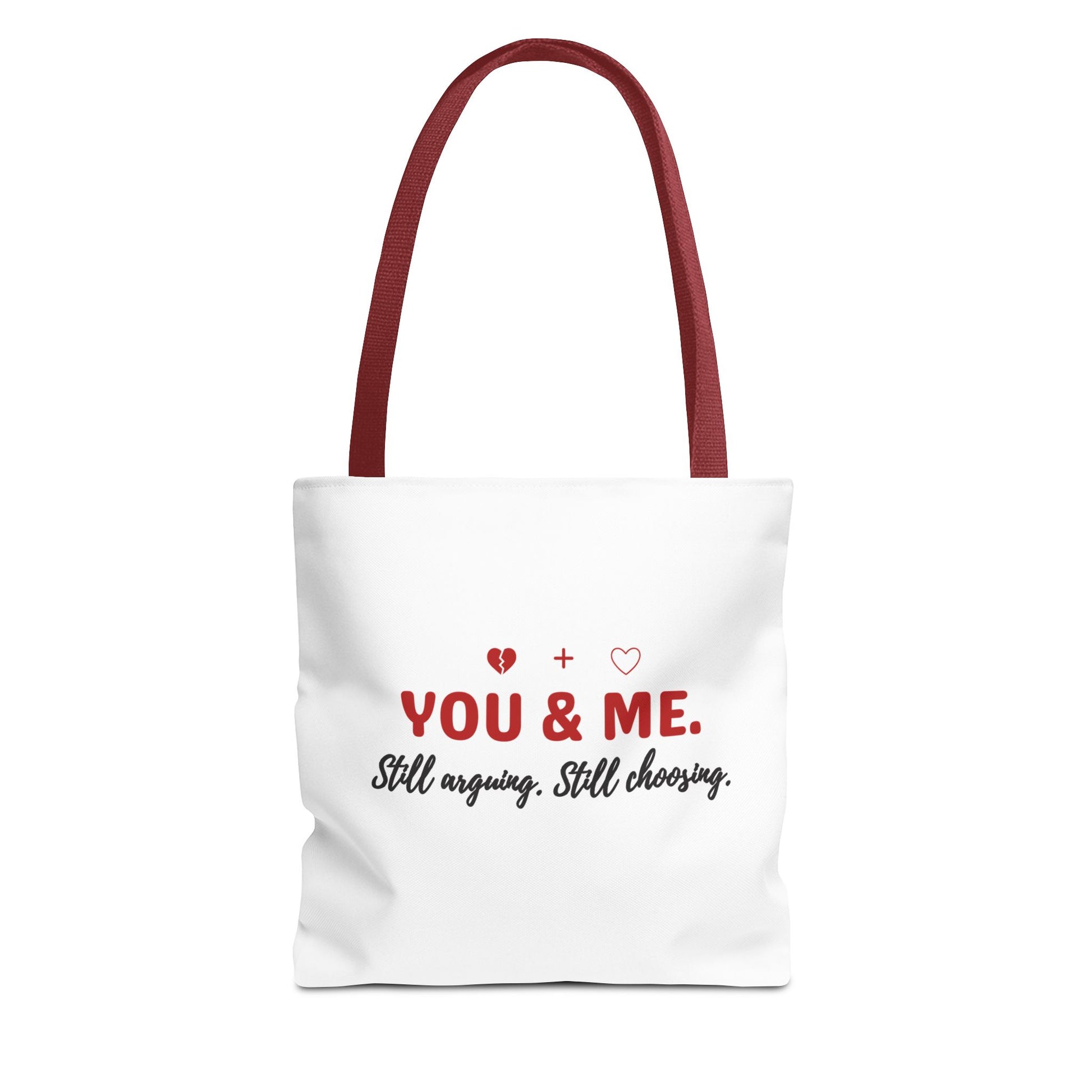 White tote bag with red handle and text 'YOU & ME. Still arguing. Still choosing.' on a white background