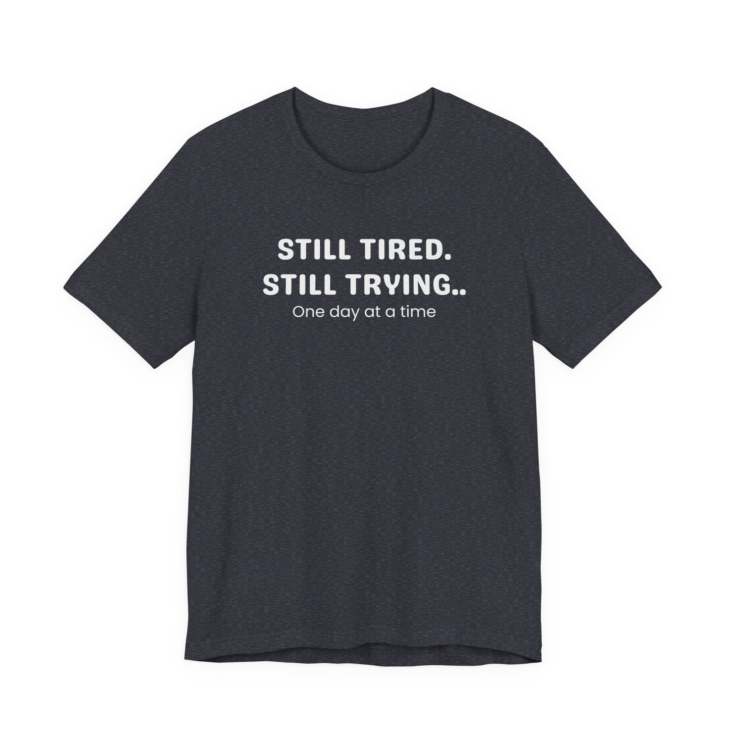 heather navy t-shirt with white text 'Still Tired. Still Trying. One day at a time' on a white background