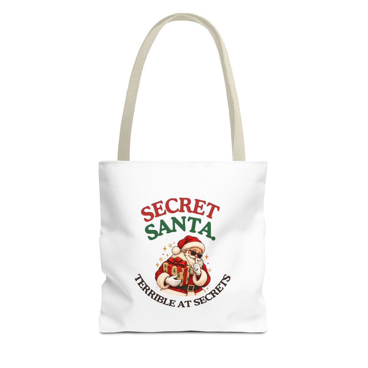 A white tote bag with beige handles featuring the “Secret Santa. Terrible at Secrets.” design on a white background