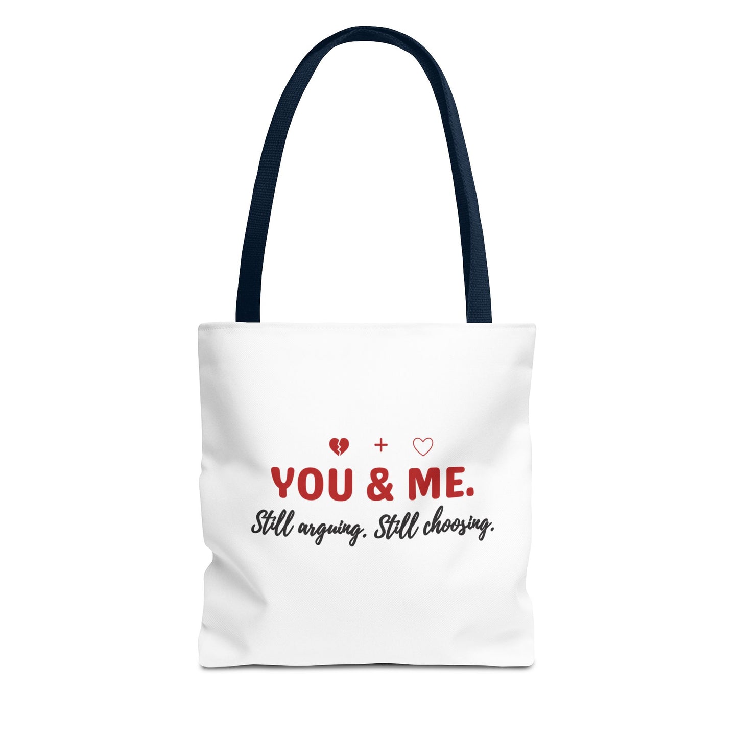 White tote bag with navy handle and text 'YOU & ME. Still arguing. Still choosing.' on a white background